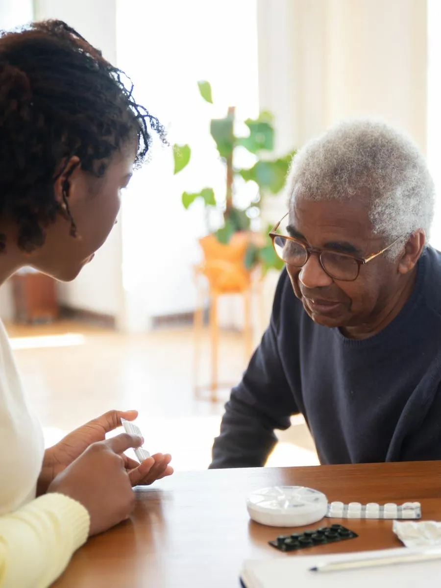 Caregiver reviewing medications with an older adult at a table